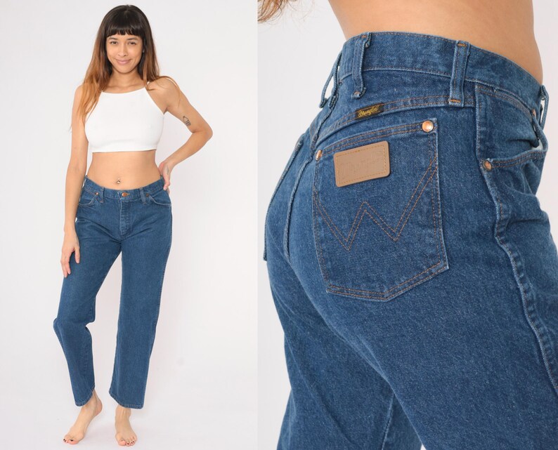 May include: A pair of blue denim jeans with a brown leather patch on the back pocket that says "Wrangler".