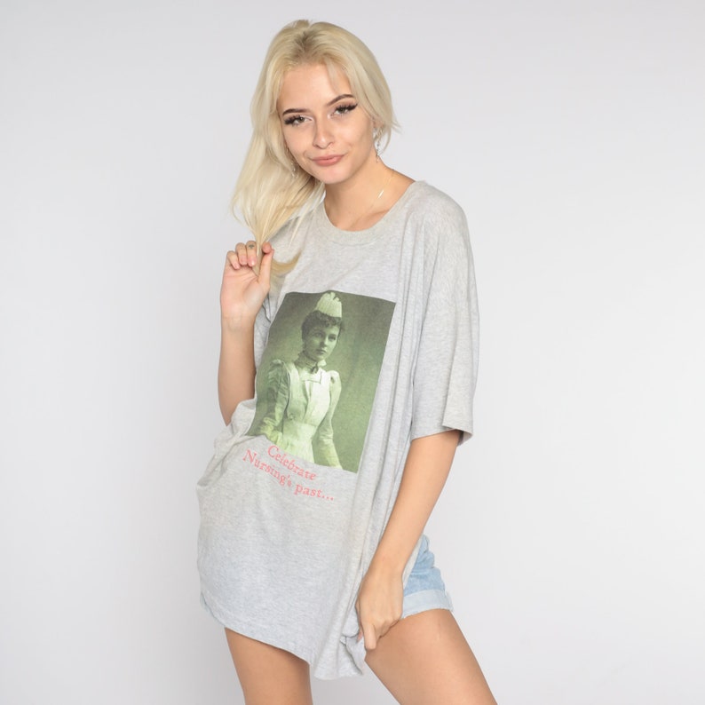 May include: A gray oversized t-shirt with a vintage image of a nurse and the text "Celebrate Nursing's past..."