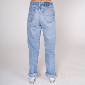 May include: A pair of light blue denim jeans with a cuffed hem. The jeans have a classic five-pocket style and a straight leg.
