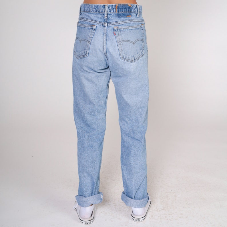 May include: A pair of light blue denim jeans with a cuffed hem. The jeans have a classic five-pocket style and a straight leg.