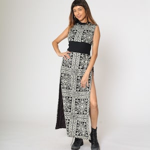 May include: A black maxi dress with a white geometric pattern and side slits. The dress has a high neckline and a fitted bodice.
