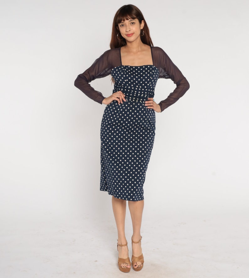 May include: A navy blue midi dress with white polka dots and a sheer black overlay. The dress has a square neckline and a fitted silhouette.