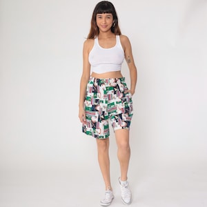 Op de afbeelding: Witte tanktop en een korte broek met patroon. De korte broek heeft een kleurrijke print met groene, rode en zwarte geometrische vormen en figuren op een witte achtergrond. De korte broek heeft een elastische tailleband.