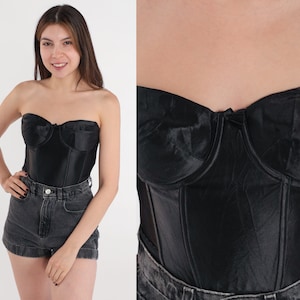 Puede incluir: Un cors&eacute; negro de sat&eacute;n sin tirantes con varillas y escote de coraz&oacute;n.