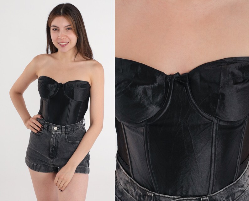 Puede incluir: Un cors&eacute; negro de sat&eacute;n sin tirantes con varillas y escote de coraz&oacute;n.