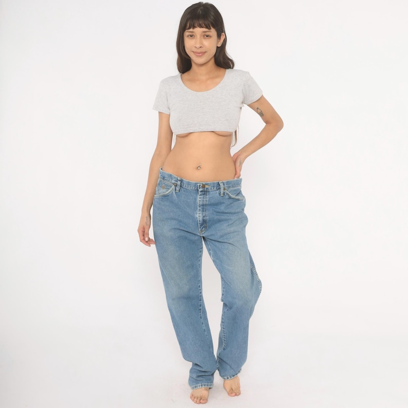 Peut inclure: Un haut court gris clair et un jean en denim bleu clair. Le haut &agrave; manches courtes a une encolure arrondie. Le jean est de couleur claire avec une coupe d&eacute;contract&eacute;e. Le mod&egrave;le se tient devant un fond blanc.