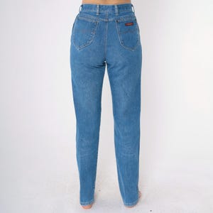 Op de afbeelding: Een paar blauwe jeans met een hoge taille en een rechte pijp. De jeans heeft een klassiek ontwerp met vijf zakken en een klein rood label op de rechter achterzak.