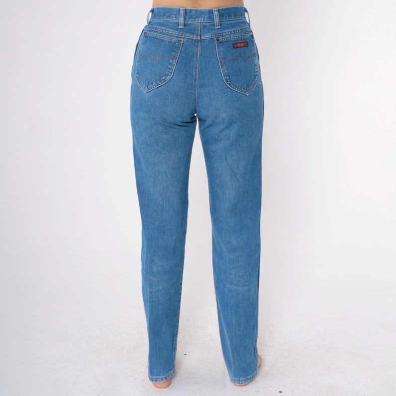 Op de afbeelding: Een paar blauwe jeans met een hoge taille en een rechte pijp. De jeans heeft een klassiek ontwerp met vijf zakken en een klein rood label op de rechter achterzak.