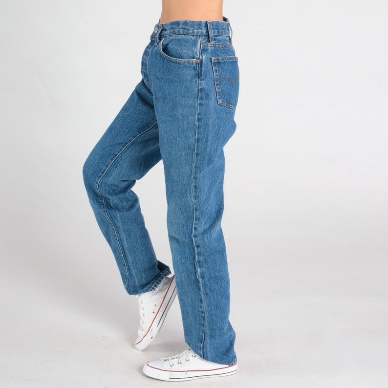 May include: A pair of blue denim jeans with a straight leg fit. The jeans have a classic five-pocket style and a button fly.