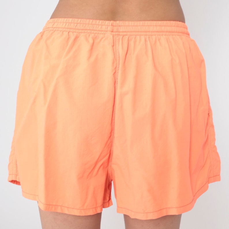 May include: A pair of bright orange athletic shorts with an elastic waistband.
