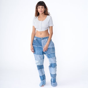 May include: A person wearing a grey cropped top and blue denim jeans made of multiple panels of denim sewn together.