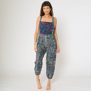 Puede incluir: Un mono colorido con un corpiño floral y pantalones estampados. La parte superior es azul oscuro con un diseño floral en tonos morados, turquesas y verdes. Los pantalones tienen un patrón a juego en colores similares.