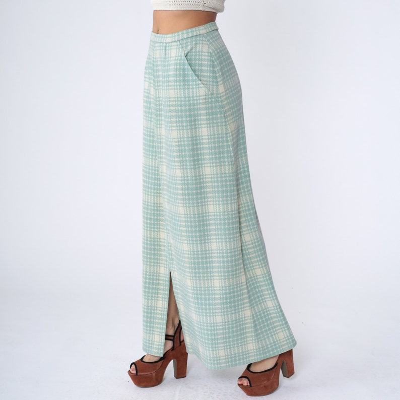 May include: A long, light blue skirt with a white plaid pattern. The skirt has a slit up the front and a pocket on the right side.