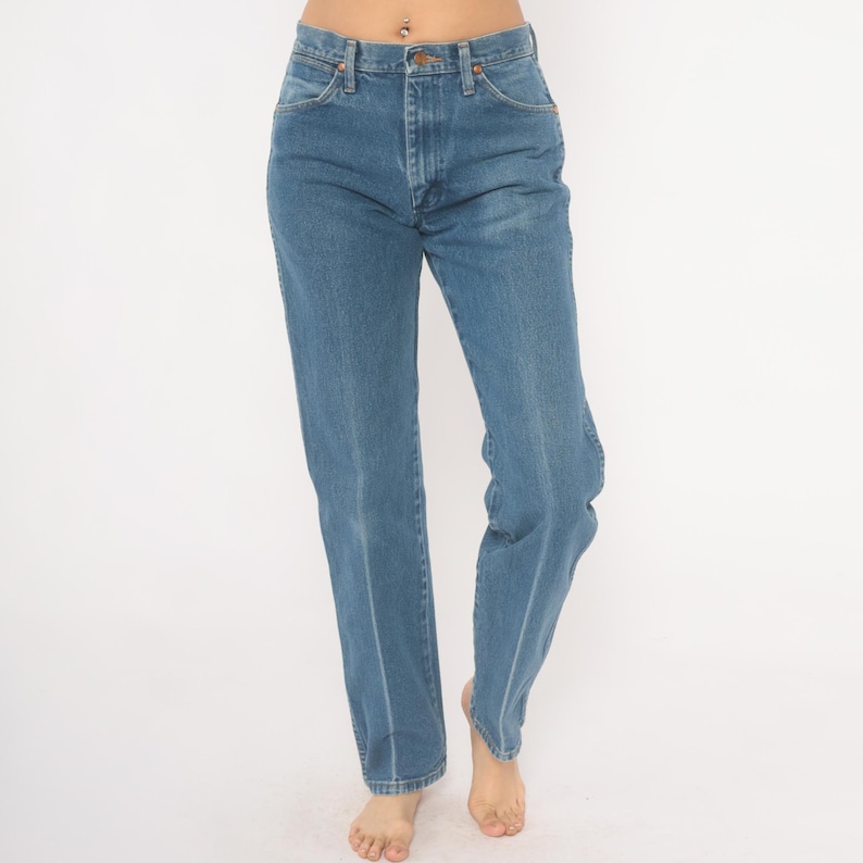 May include: Light blue denim jeans with a classic straight-leg fit. The jeans feature a button and zipper closure, front and back pockets, and a light wash. The jeans are a timeless wardrobe staple.