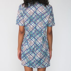 Puede incluir: Un vestido de manga corta con un patr&oacute;n geom&eacute;trico en tonos de azul, gris y blanco. El vestido tiene un cuello y una silueta recta.