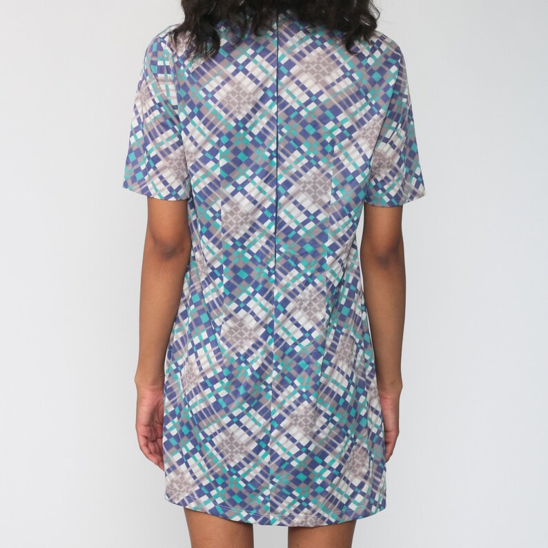 Puede incluir: Un vestido de manga corta con un patr&oacute;n geom&eacute;trico en tonos de azul, gris y blanco. El vestido tiene un cuello y una silueta recta.