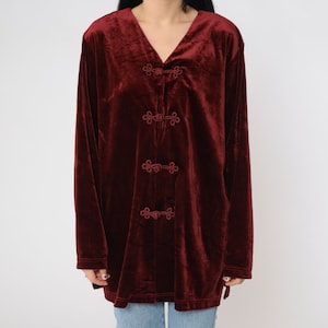 May include: A long-sleeved burgundy velvet shirt with a V-neck and decorative button closures.