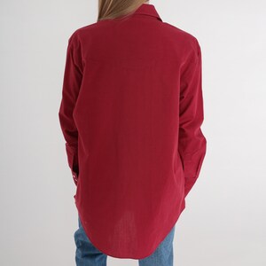 May include: A long-sleeved, button-down shirt in a deep burgundy red colour. The shirt has a classic collar and a relaxed fit.