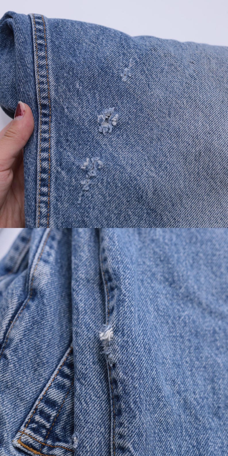May include: Close-up of light blue denim fabric with several small holes. The fabric is folded and shows the stitching along the edge.