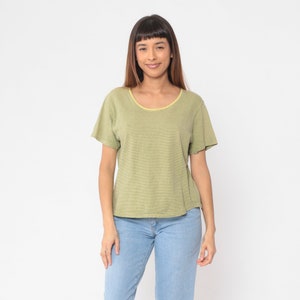 Peut inclure: Un t-shirt &agrave; rayures vertes et jaunes avec un col rond et des manches courtes. L'encolure est bord&eacute;e de jaune. Le t-shirt est associ&eacute; &agrave; un jean bleu clair.