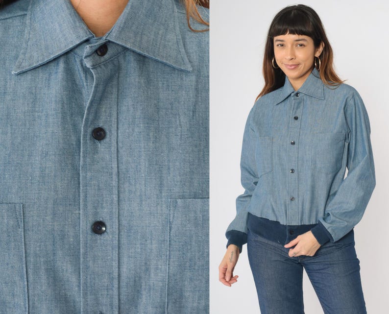 May include: A light blue denim shirt with a button-up front and long sleeves. The shirt has a collar and a pocket on the left chest.