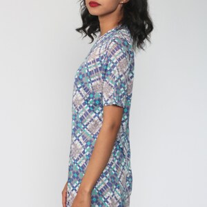 Puede incluir: Un vestido de manga corta con un patr&oacute;n geom&eacute;trico en tonos azules, verdes y grises. El vestido tiene un escote redondo y un ajuste holgado.