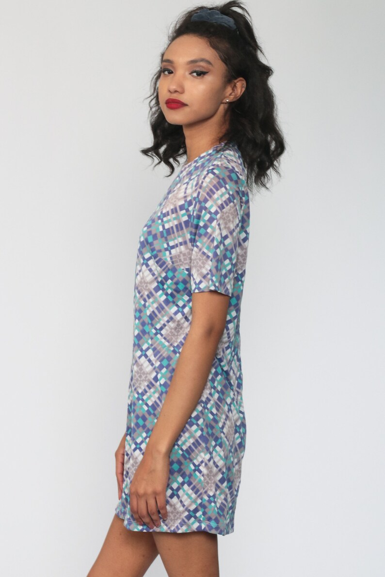 Puede incluir: Un vestido de manga corta con un patr&oacute;n geom&eacute;trico en tonos azules, verdes y grises. El vestido tiene un escote redondo y un ajuste holgado.