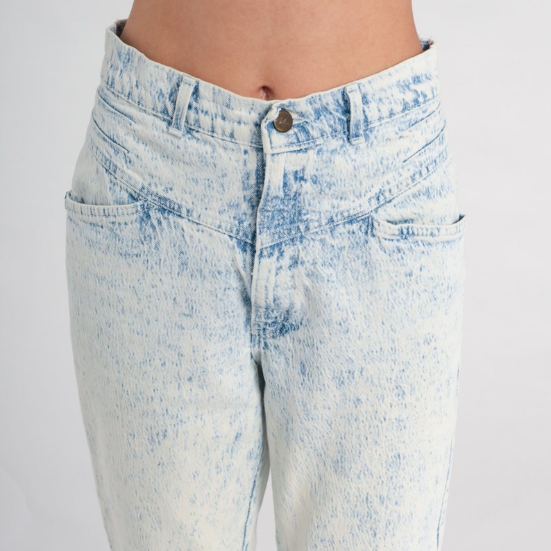 May include: Light blue acid wash denim jeans with a high waist and a relaxed fit.