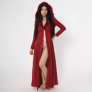 Puede incluir: Una larga bata roja con capucha forrada de piel. La bata tiene una abertura en la parte delantera y una larga abertura en la parte delantera.
