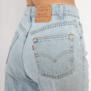 May include: Light blue denim jeans with a classic five-pocket design. The back features a Levi Strauss & Co. leather patch and a red tab on the back pocket. The jeans have a straight leg cut.