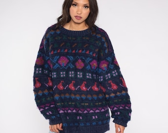 May include: A navy blue sweater with a colorful geometric pattern. The pattern includes pink, purple, blue, and green shapes. The sweater has a crew neck and long sleeves. The sweater is made of a soft, textured material.