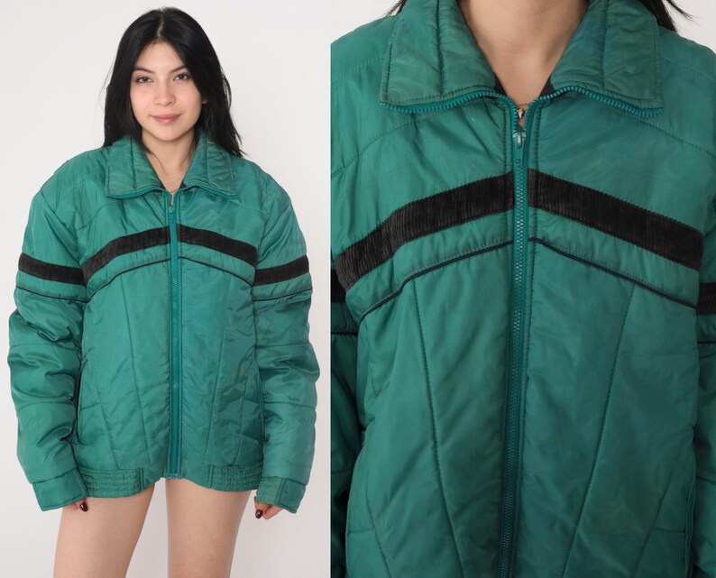 May include: A green quilted jacket with black and brown stripes. The jacket has a zipper closure and a stand-up collar.