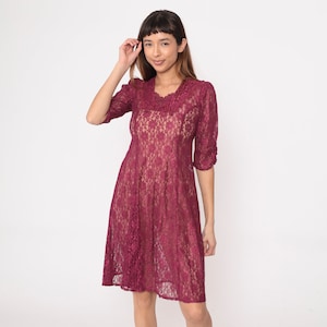 Peut inclure: Une robe en dentelle bordeaux avec un décolleté en V et des manches 3/4. La robe a un corsage ajusté et une jupe ample.