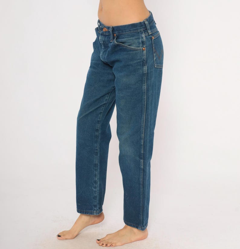May include: Blue denim jeans with a classic straight-leg fit. The jeans have a button and zipper closure, front and back pockets, and belt loops. The denim is a medium wash with subtle fading and wear.