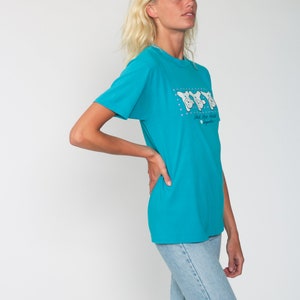 May include: A turquoise blue t-shirt with a graphic of three cartoon bears wearing sunglasses and the text "Head for the Hills" with a small logo below.