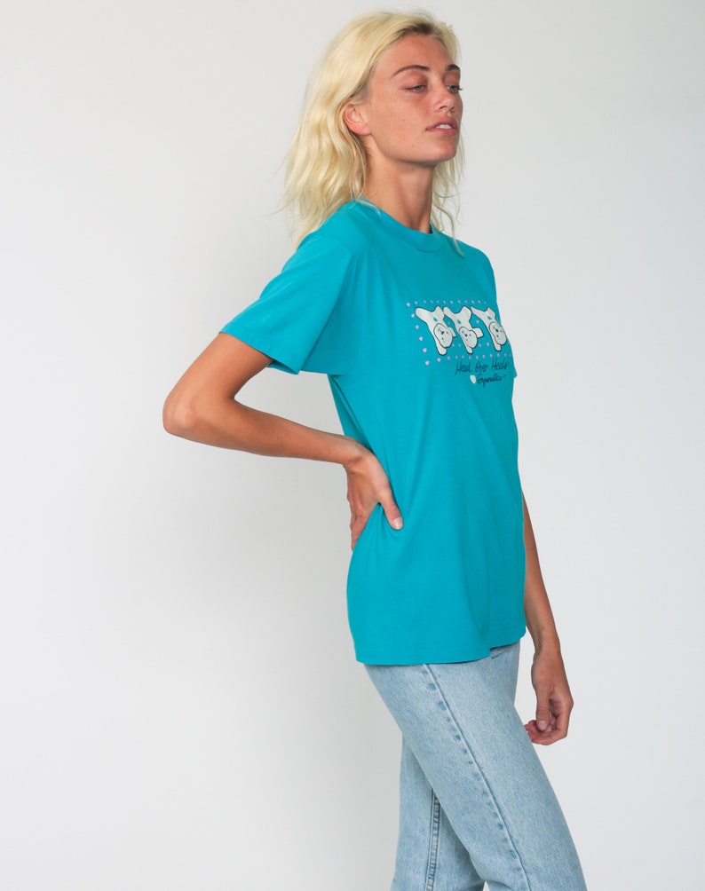 May include: A turquoise blue t-shirt with a graphic of three cartoon bears wearing sunglasses and the text "Head for the Hills" with a small logo below.