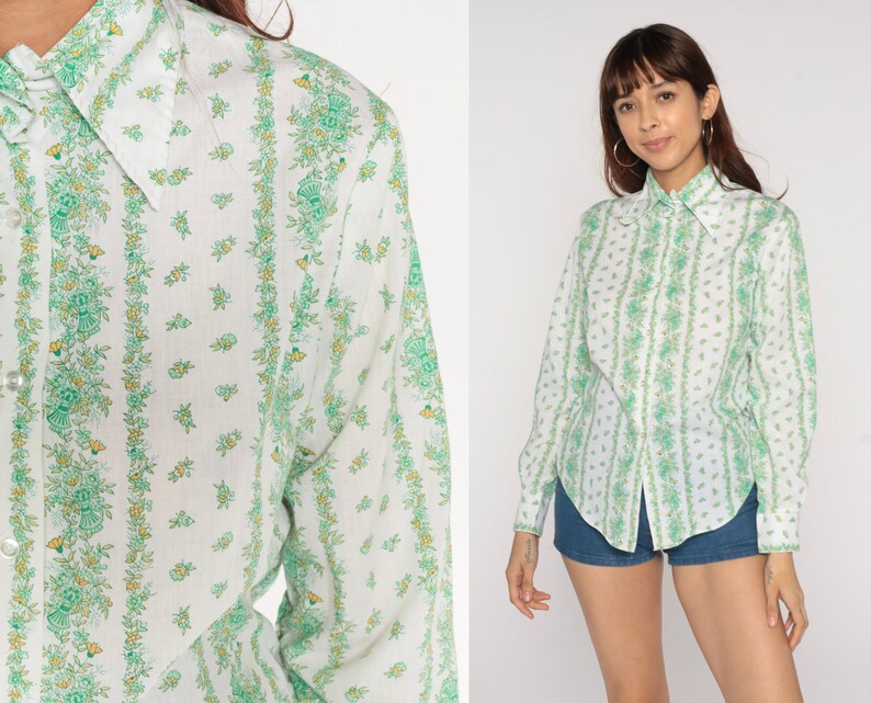 Puede incluir: Una camisa blanca de manga larga con botones y estampado floral verde y blanco. La camisa tiene un cuello puntiagudo y cierre de botones en la parte delantera.