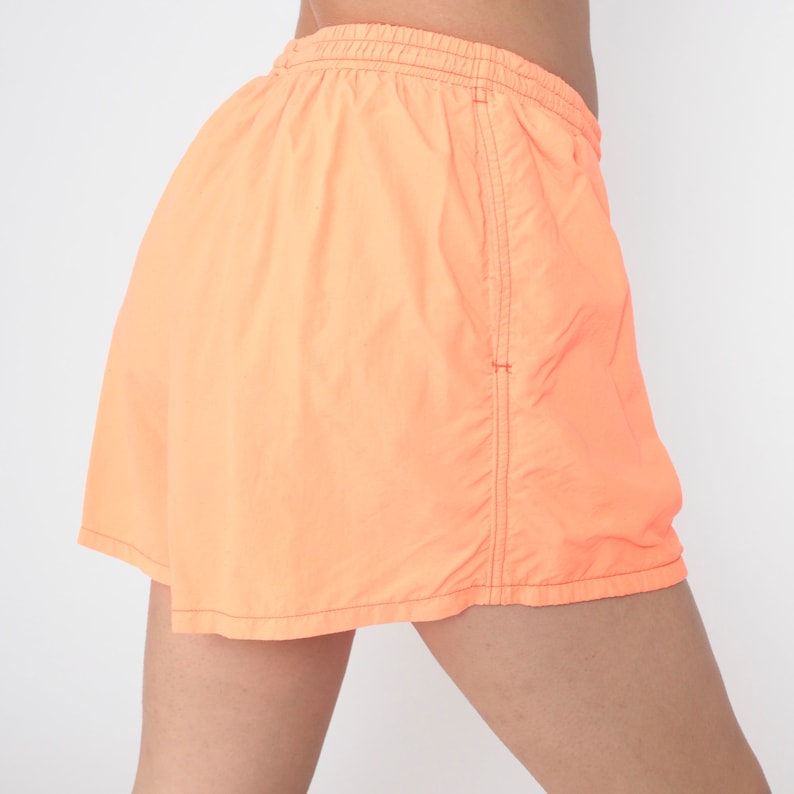 May include: A pair of bright orange shorts with a drawstring waist and side seam detail.