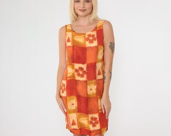 May include: A sleeveless dress with a geometric pattern in shades of orange and yellow. The dress has a scoop neck and a straight silhouette.