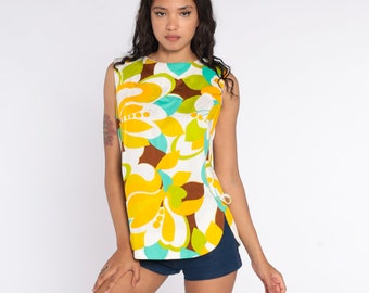 May include: A sleeveless top with a white background and a colorful floral print in shades of yellow, green, blue, and brown. The top has a scoop neck and a loose fit.