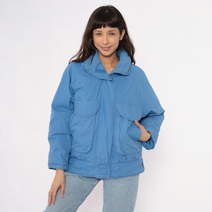 Peut inclure: Veste bleu clair avec un col montant et deux grandes poches avant. La veste a une coupe ample et une fermeture boutonnée. Le modèle porte la veste avec un jean bleu clair.