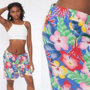 May include: Blue shorts with a vibrant floral pattern featuring pink, red, and yellow flowers, along with green leaves. The shorts have an elastic waistband and a relaxed fit, perfect for casual wear.