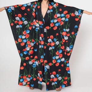 May include: A black kimono with a floral print featuring red, blue, and white flowers. The kimono has long sleeves and a wide, flowing silhouette.