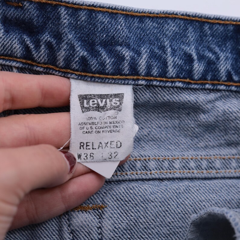 May include: A blue denim Levi's label with white text. The label says "100% Cotton", "Assembled in Mexico of U.S. Components", "Care on Reverse", "Relaxed", "W36 L32".