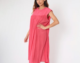 Könnte beinhalten: Ein rosafarbenes Midikleid mit einem gerafften Rock und einem runden Ausschnitt. Das Kleid hat einen strukturierten Stoff und ist ärmellos.