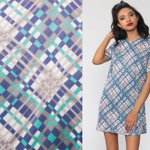 Puede incluir: Un vestido de manga corta con un patr&oacute;n geom&eacute;trico en tonos de azul, verde y blanco. El vestido tiene una silueta simple y cl&aacute;sica.