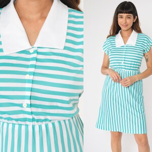 May include: A short-sleeved, turquoise and white striped dress with a white collar and button closure. The dress has a fitted bodice and a slightly flared skirt.