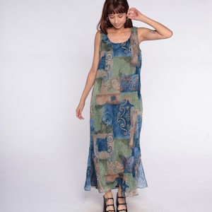 May include: A sleeveless maxi dress featuring a patchwork design in shades of blue, green, and brown. The dress has a scoop neckline and a flowing silhouette. The fabric appears lightweight and suitable for warm weather.