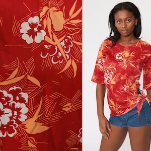 May include: Red and orange floral print short-sleeved shirt with a tie at the side. The shirt has a relaxed fit and a round neckline.