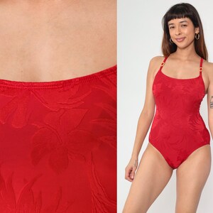 Peut inclure: Maillot de bain rouge &agrave; motif floral. Le maillot de bain a des bretelles fines et un d&eacute;collet&eacute; arrondi.